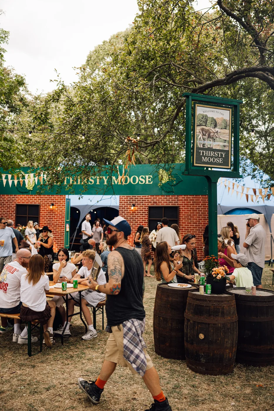 The Thirsty Moose bar at the festival, with a pub sign, barrels and people at tables