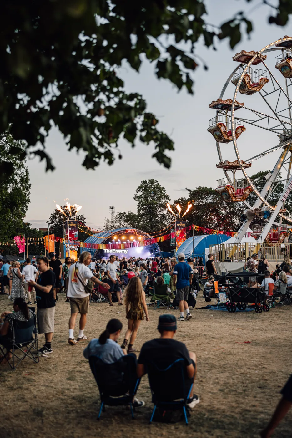 People sitting on the grass with a big wheel behind them