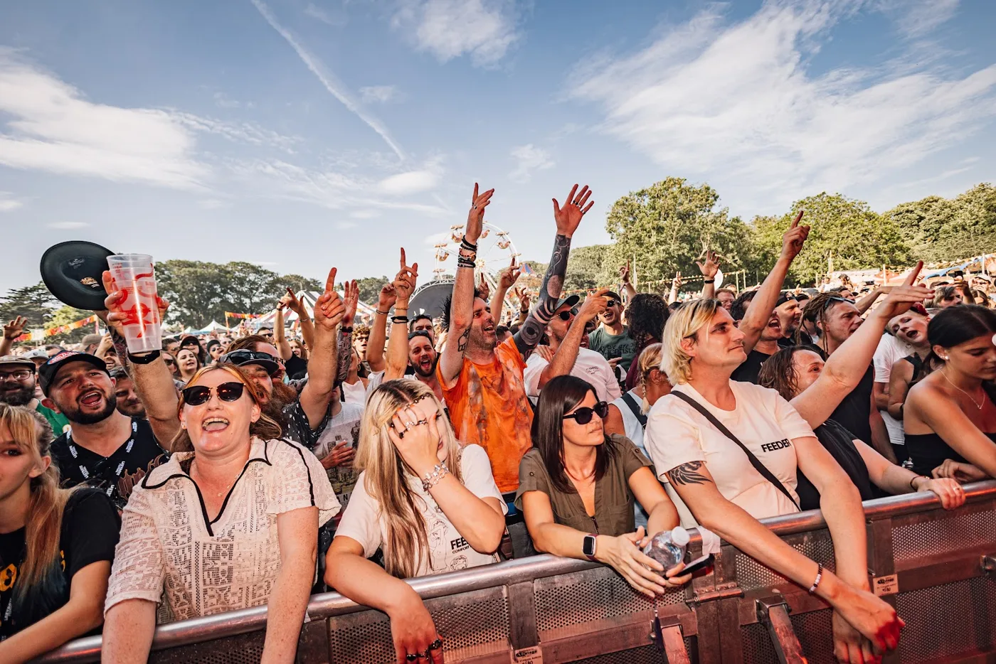 Festival-goers cheering and singing at the front barrier in front of a stage
