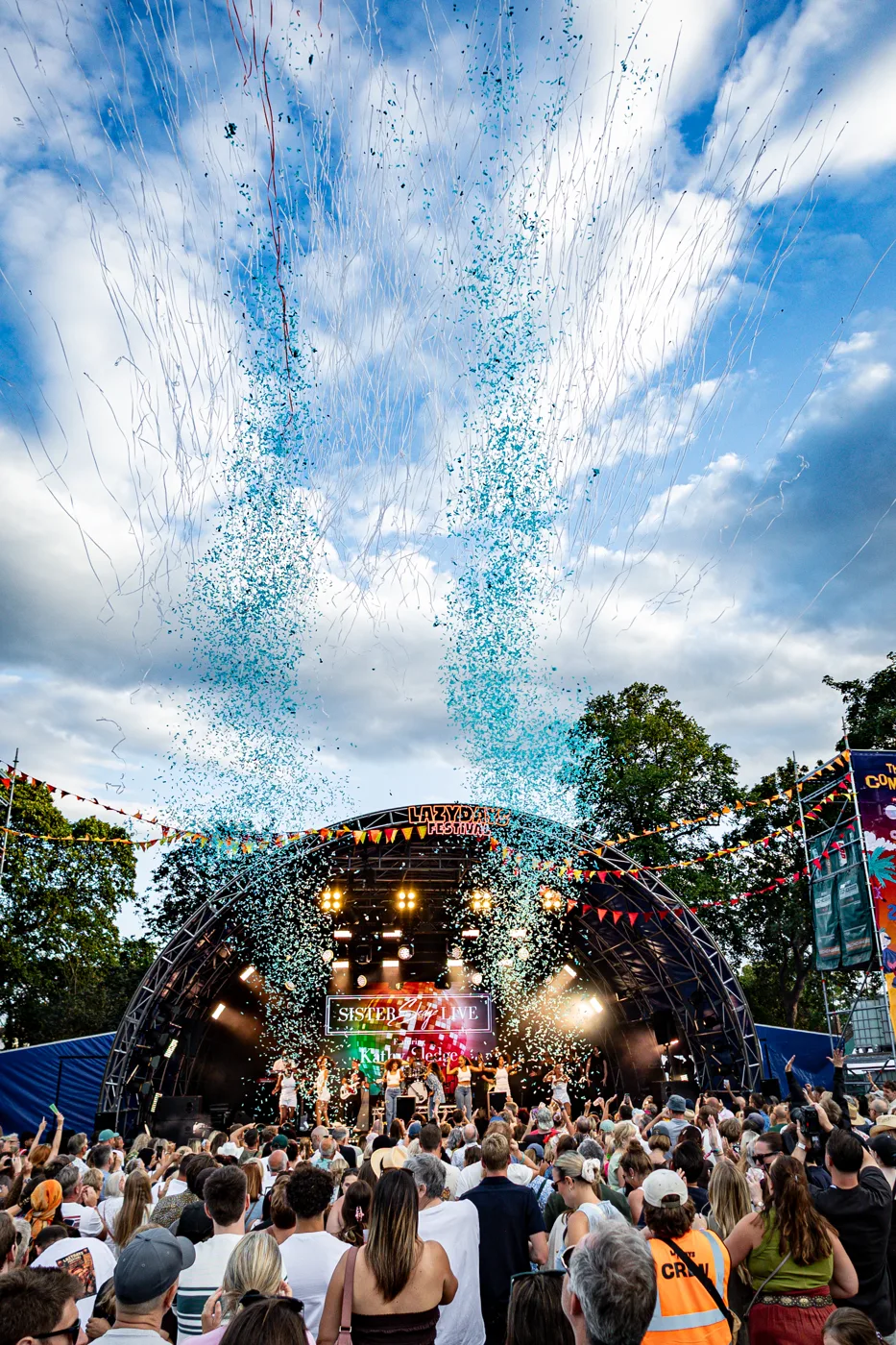 Blue confetti blasting into the sky above the main stage and crowd