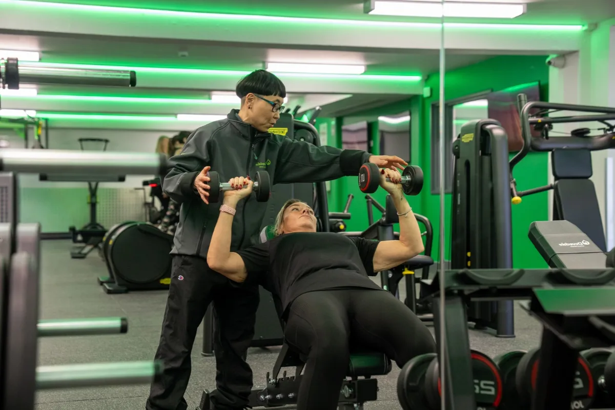 An instructor works with a woman on the free weights in the gym at Dovedale Leisure Centre.